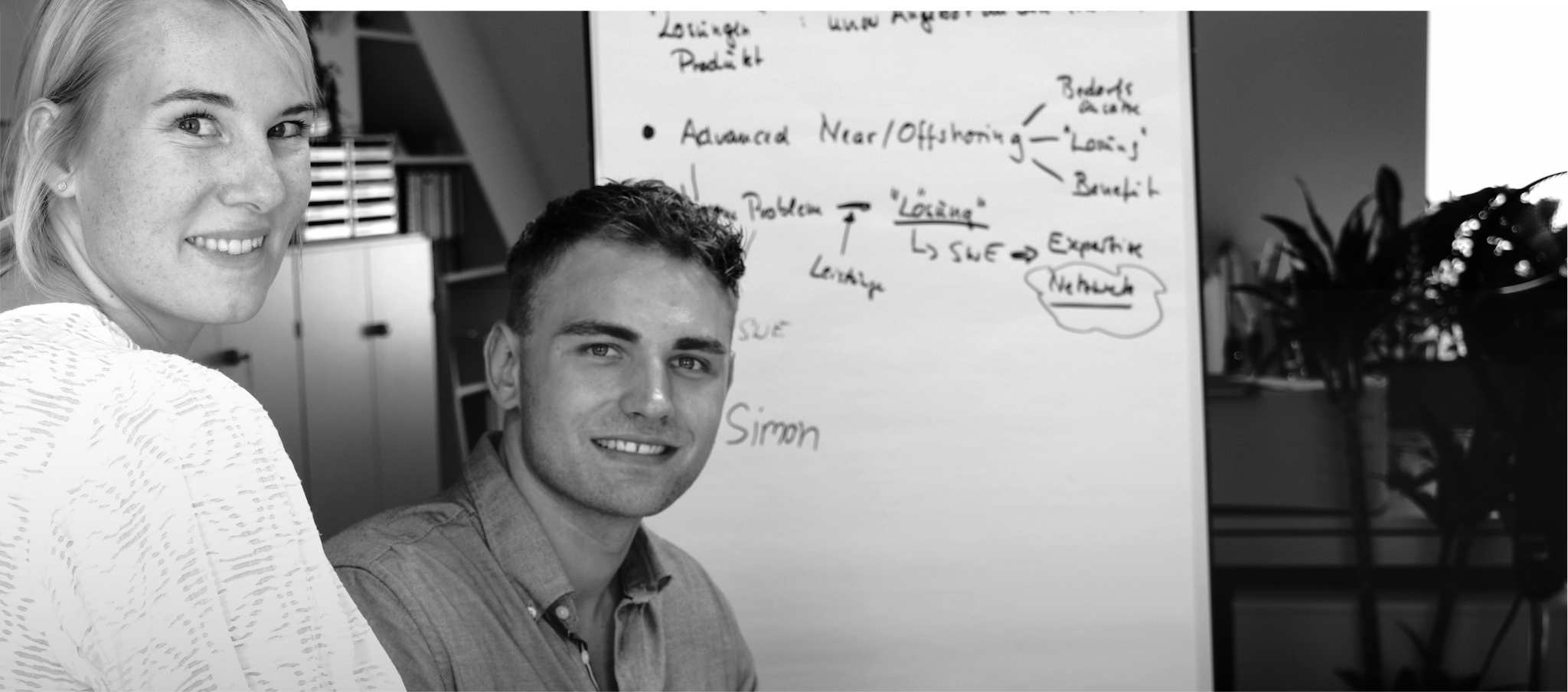 Schwarz-weiß-Bild. Simon und Ricarda schauen direkt in die Kamera und lächeln.