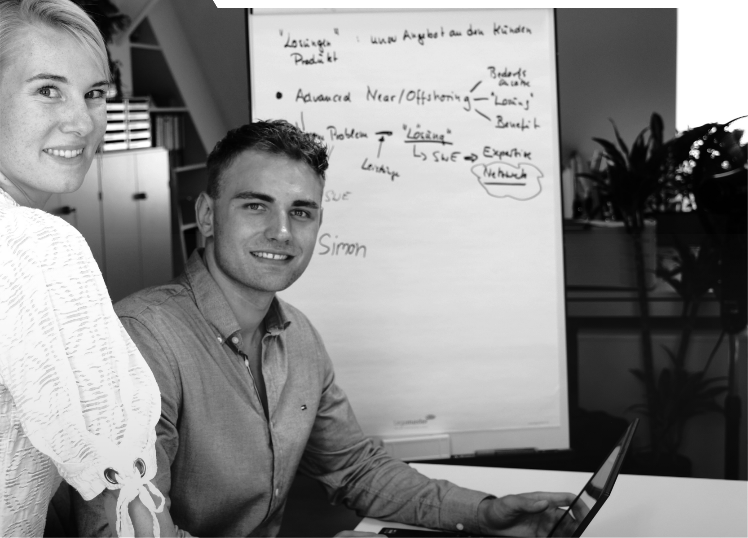 Schwarz-weiß-Bild. Simon und Ricarda schauen direkt in die Kamera und lächeln.